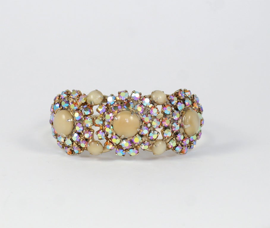 Three large creamy beige cabochon stones surrounded by aurora borealis rhinestones and four additional smaller cabochons on a clamp style bracelet.