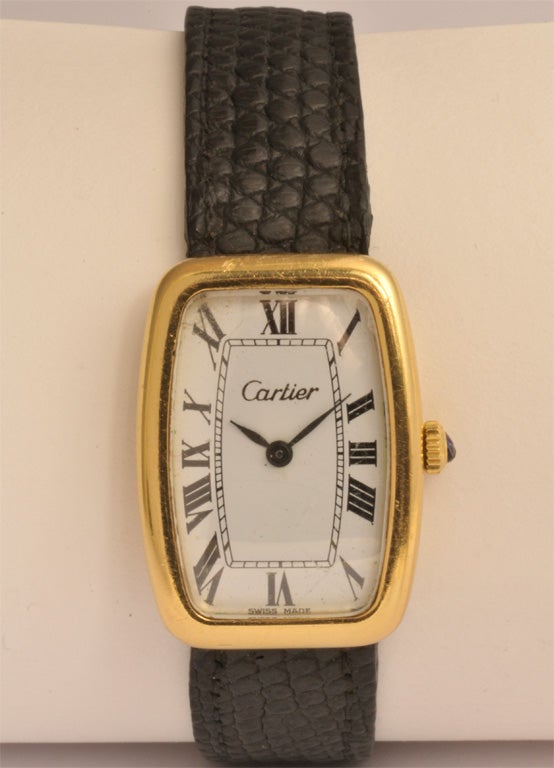 An 18K yellow gold men's mechanical Cartier wristwatch with 18K yellow gold deployant embellished with a sapphire cabochon and leather bracelet.