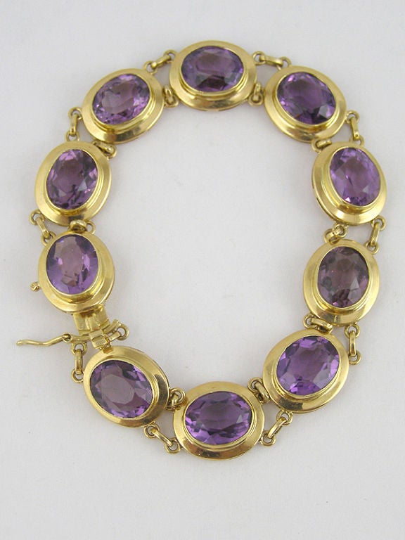 18K yellow gold bracelet with 10 well matched 7mm x 9mm oval amethyst in simple bezel settings with a raised, finished gallery divided by round loops and hidden box clasp. 7