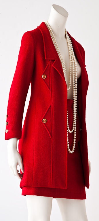 Red wool boucle Chanel suit with 3/4 length jacket and straight skirt. Jacket is cut in the typical Chanel fashion with tight armhole and slender fitting body. Jacket has narrow lapels, double seam details on jacket body and skirt. Red 