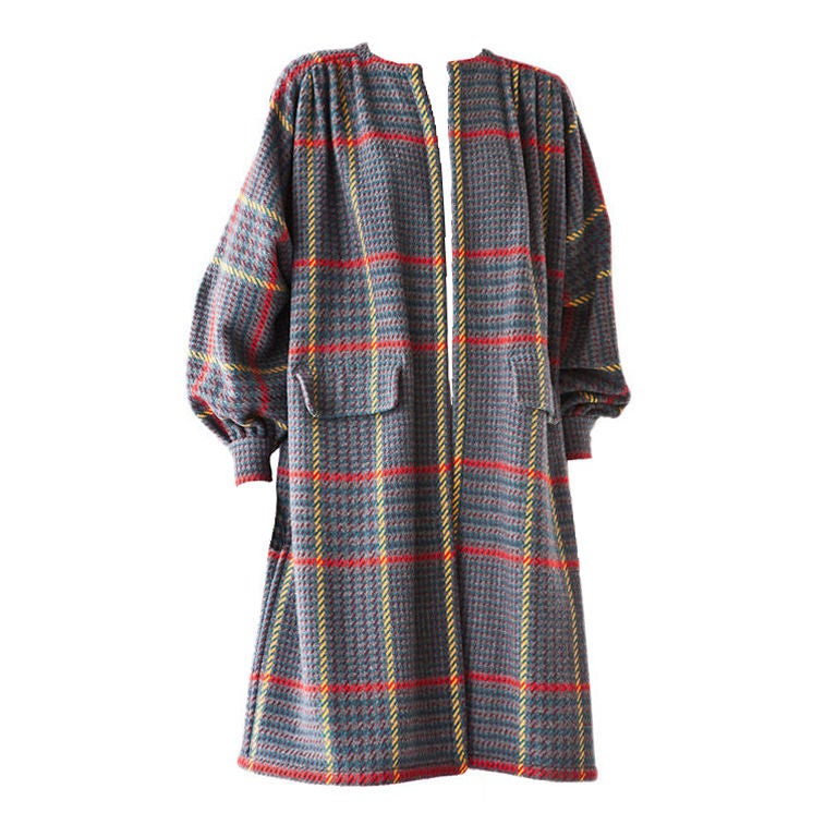 Valentino wool plaid smock style coat with gathered yoke and full<br />
sleeves that end in a tight cuff. Coat has a gray background with shades of ochre, red, brown and green creating a bold plaid pattern.