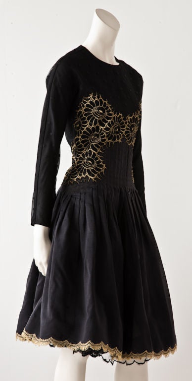 Geoffrey Beene shimmery black silk organza multi layered dress with gold metallic lace embroidery detail on bodice. Dress has point d'esprit lace sleeve and upper bodice. There is pleating detail at lower bodice near waist and skirt breaks into