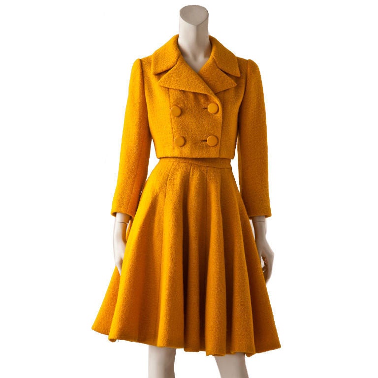 Norman Norell marigold colored 2 piece wool boucle suit.<br />
Jacket is double breasted, fitted, cropped and reaches just above the waist. Skirt is gored with many panels creating a generous 