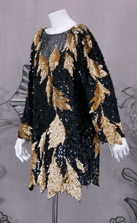 Beaded and sequinned minidress with gold foliates on a black ground. Slips over head like oversized T shirt.Organic leaf shaped hem and sleeve hem.<br />
Silk chiffon base with pronged rhinestone accents on sheer neckline.<br />
Size: L (US)