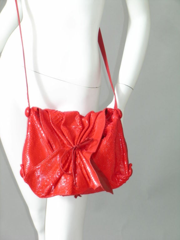 Cheerful and bright, red snakeskin makes this gorgeous shoulder bag from Carlos Falchi pop with color and style.<br />
<br />
The gathered front flap has a red leather tie at the center and the bag has a matching red leather drawstring.  The
