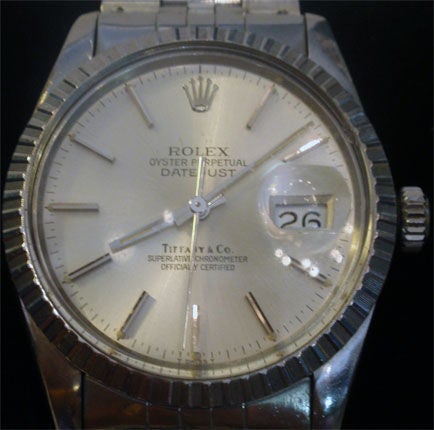 This is a very rare, collectible stainless steel, with white gold bezel Rolex for Tiffany, Oyster Perpetual DateJust watch for men, Circa 1972. It has a white  colored face, and a 'plastic' cover. As with all DateJust Rolex watches there is a small