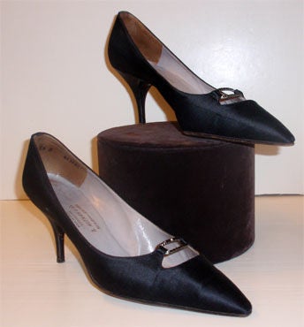 This is a sophisticated pair of vintage evening shoes from Charles Jordan. They are black satin with a stiletto heel, pointed toe, and leather sole. There is a metal buckle detail at the toe with black rhinestones.

Size 8 1/2A