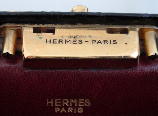 This is a rare collectible black alligator jewelry box handbag by HERMES, from 1950. It has one main burgundy leather compartment with two open interior slit pockets. Underneath sits a burgundy leather jewelry box with a matching velvet pillow. This