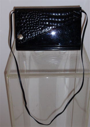 This is a vintage alligator, lucite, and leather clutch or handbag by Andro's, from 1950. It has an alligator flap with a lucite case, and leather sides. There is one main compartment with one open side pocket and a detachable 20
