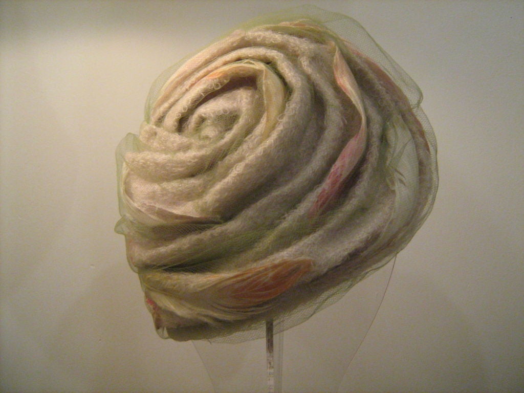 This is a beautifully made, very rare Christian Dior piece. In incredible condition, this soft folded turban style hat has a pastel green net overlay. Inside the folds you will find gorgeous feathers ranging in colors from peach to raspberry to