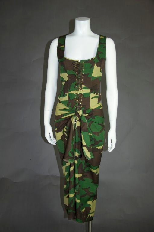 Three piece camouflage suit. Skirt is a sarong style with a split up the front with one leather buckle and a tie at the hip front, zip back. Blouse is a corset style bustier with rope tie up front and zip back. The corset top is lined, creating a