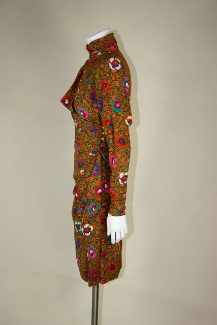 Indonesian batik inspired floral print with block color flowers. Gathered at waist on left side completing a warp around pattern with a cascading swag. Large shoulder pads, gold buttons on the front neck and the left waist. Full length sleeves with