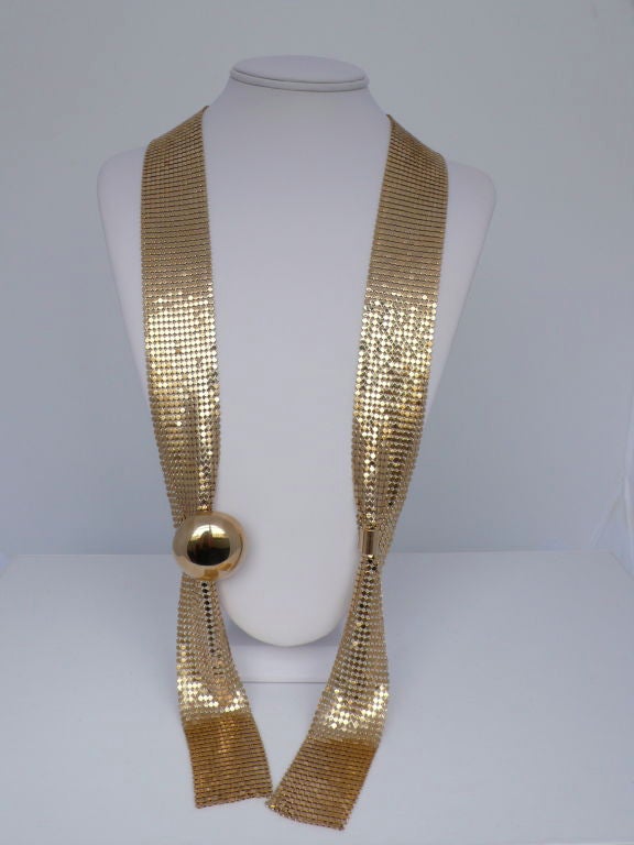 Gold metal mesh lariat with clasp at gold tone dome in center.