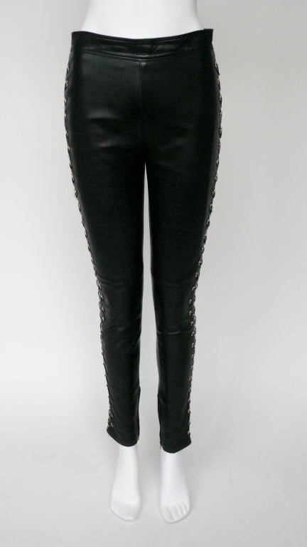 Gianni Versace high wasted leather pants. Side closings have gold gromett detailing incorporated with a leather criss cross design, and zippers detailing at ankles.