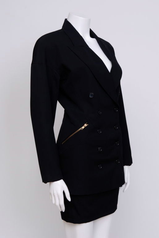 Two piece black skirt suit. Skirt is high waisted. Jacket has dolman sleeves, metal buttons, zippered pockets and shoulder pads, fully lined. Tags removed.