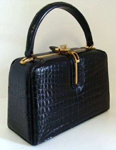 Center skin black alligator structured purse with paneled gussets.  Handle very sturdy and able to stand up to frequent use.

This is a classic - compact, but capacious.  

Purse rests on two wide glides which run from front to back of bag.

