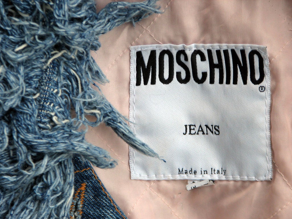 Fine vintage Moschino fringed denim jacket. Authentic 1980s item made in Italy. Jacket features full fringed cuffs & collar, quilted pink silk lining & 'Peace' sign brass button closures. Item labeled size 40 & appears to fit a modern US size 8.