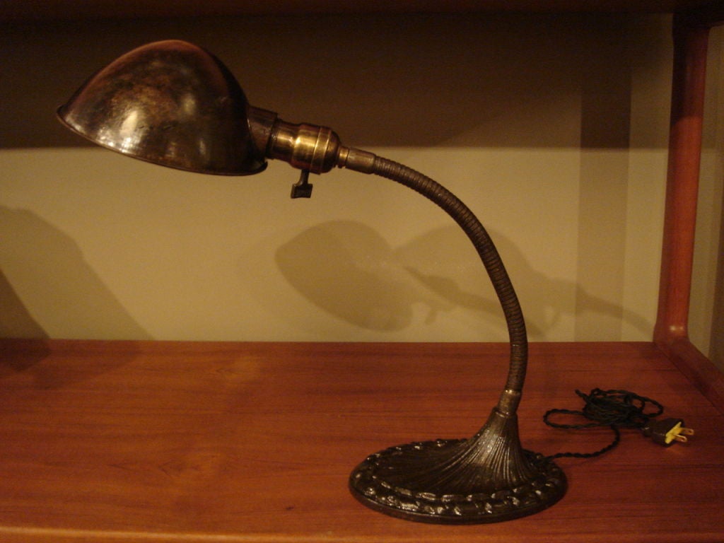 Antique industrial-style desk lamp made by the Aladdin Mfg. Company. USA, circa 1910. <br />
<br />
Features adjustable gooseneck with period-designed base and twist on-off switch. All original. Base and arm in patinated brass (black finish) with