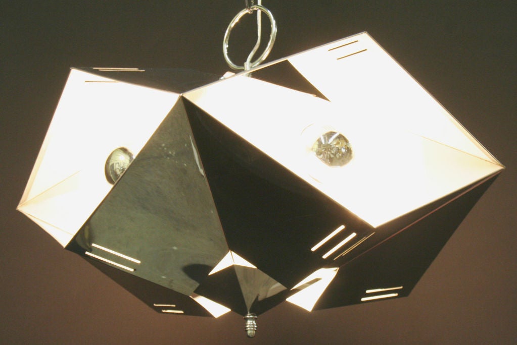A geometric french four bulb chromed pendant light with complex angular construction vented in such a way as to make the bulb invisible from below where ambient light filters through openings in the metal; four white enameled interior bays reflect a