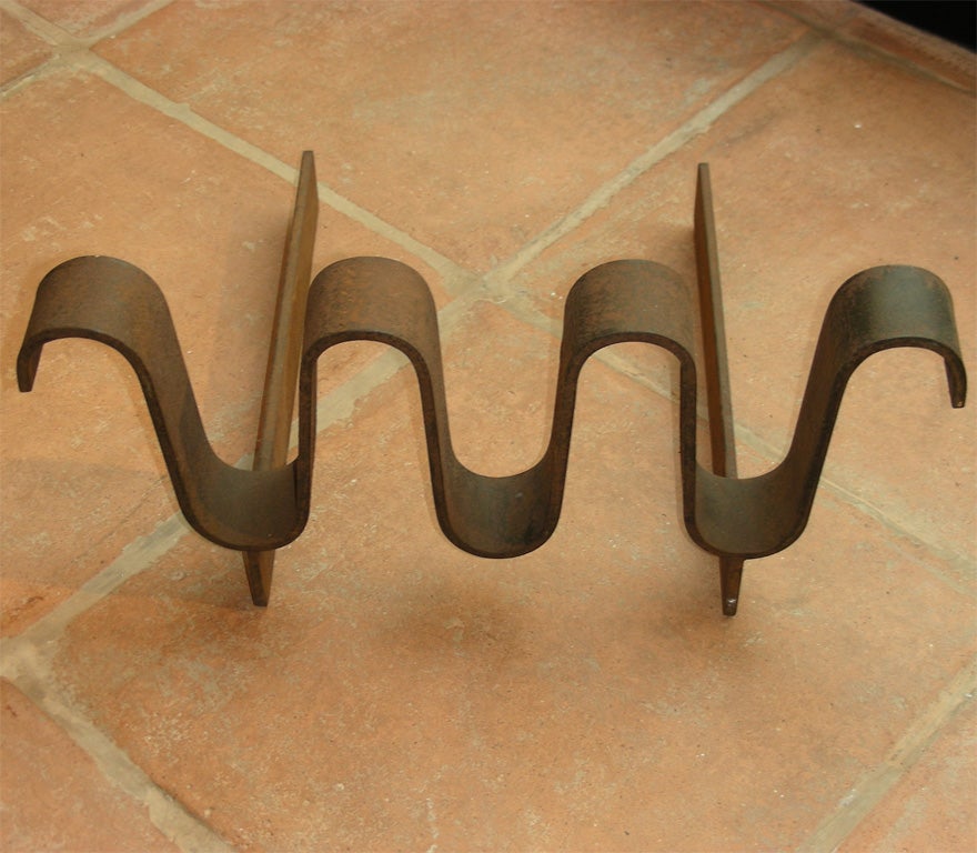1950s andiron by Jean Royere with multiple curves in the front.