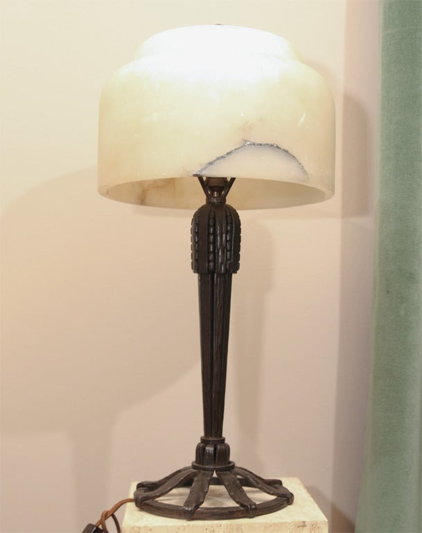 A French Art Deco wrought iron and alabaster table lamp from circa 1928, model illustrated on the cover of the 1997 Dover Edition of "French Art Deco Ironwork Designs: Raymond Subes and Others". Original shade has been repaired. New exact