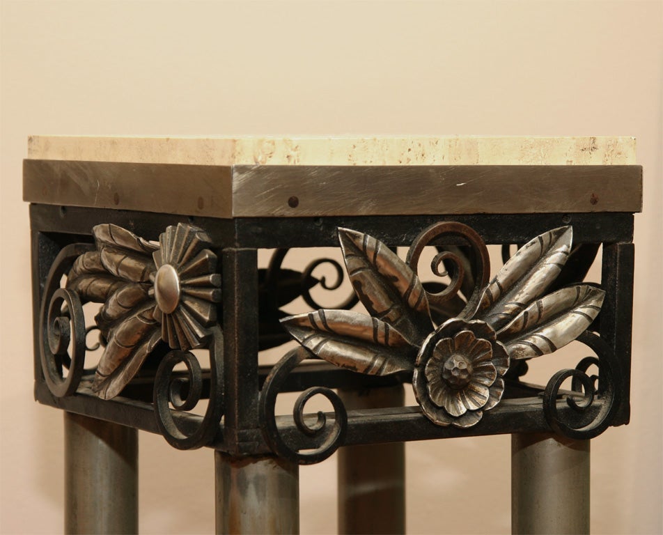 A French Art Deco pedestal, with four tubular metal uprights and travertine stone top, decorated with hammered wrought iron stylized leaves.