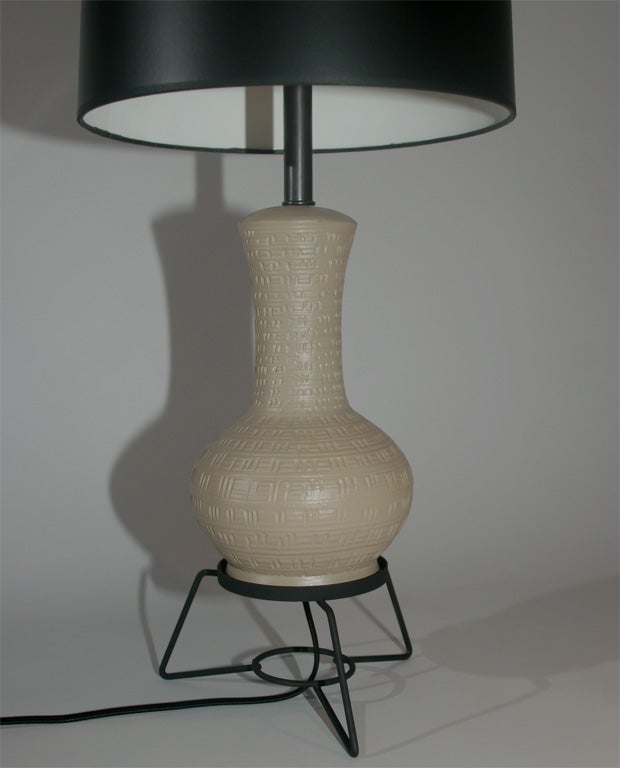 A pair of tan textured plaster urn lamps on black wire tripod bases. Bases measure 13.5