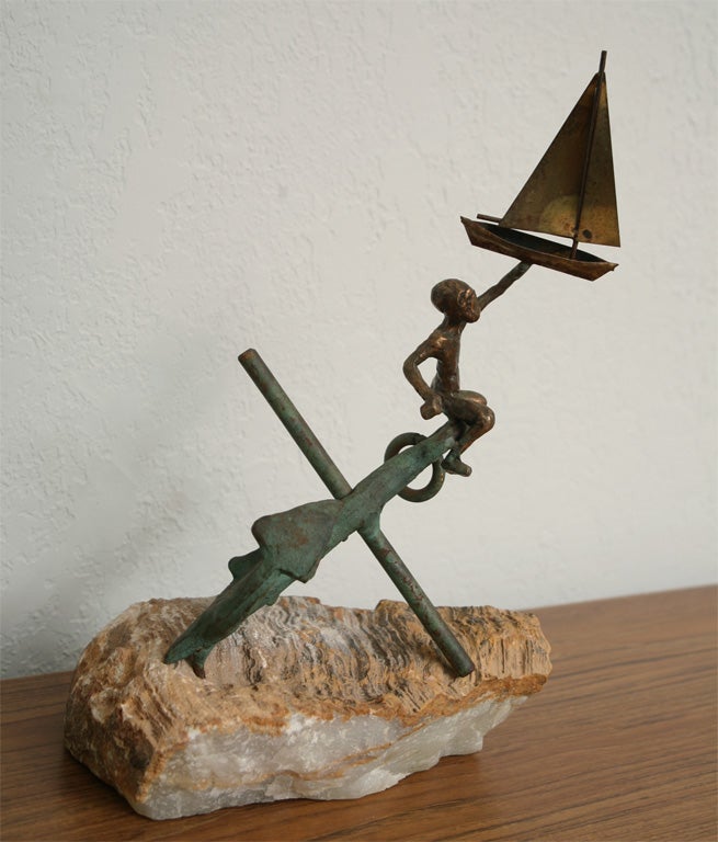 This whimsical bronze nautical sculpture captures the care-free spirit of summertime! A small boy  perched atop a patinated anchor plays with his toy sailboat, rendered in bronze and brass on a quartzite base. Signed 