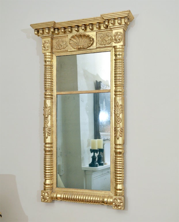 This classic American pier mirror has it all... gorgeous water-gilding, two pieces of original glass and magnificent decoration. With its center shell, acorn top gallery, bold pediment and rosette corners, this piece will add an elegant and period
