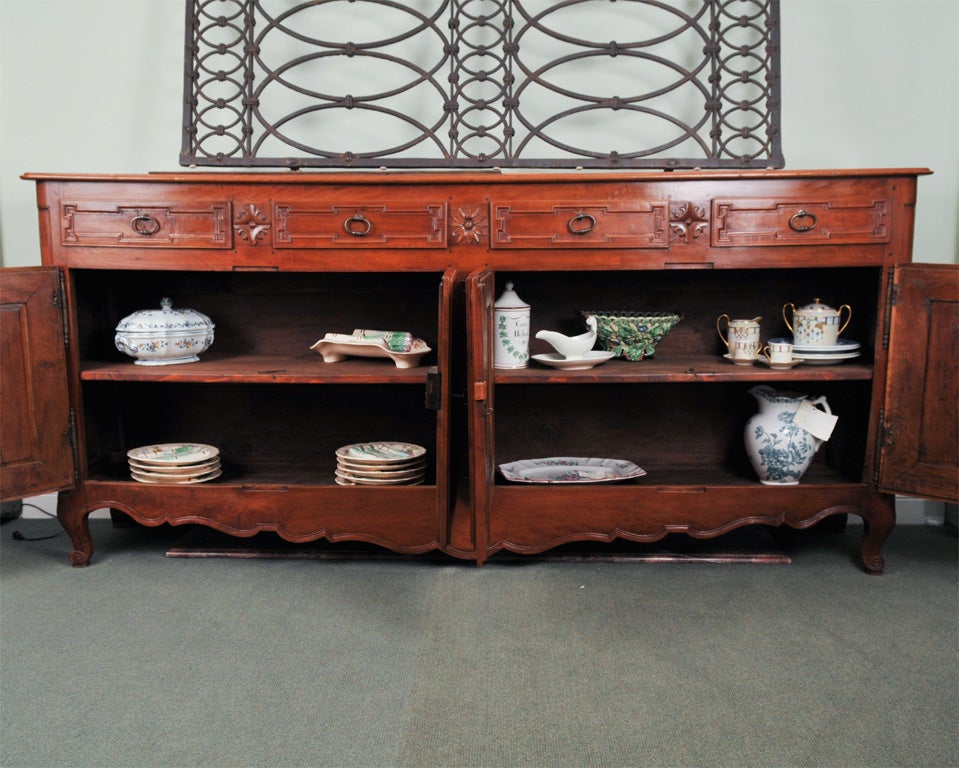 Fine French Louis XV- Louis XVI Provincial sideboard comprised of four drawers and four doors showcasing sturdy interior shleving is shown in two original woods, wild cherry and elm. This impressive piece is uncharacteristically narrow in depth for