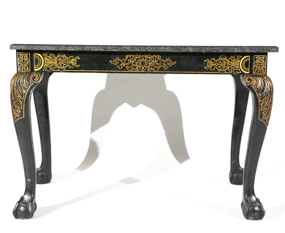 This stately center table in the Chippendale style, c. 1900-1910, has cabriolet legs which end in beautifully carved claw and ball feet. The gilt details create a dramatic backdrop for the conforming polished charcoal gray granite top. This table