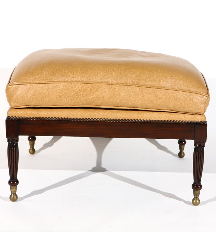 This handsome mahogany bench has reeded legs that rest upon brass ball feet. The supple leather trimmed in close-set nail heads gives this bench a classic yet comfortable feel. This piece would work well in a library or beside a fire.