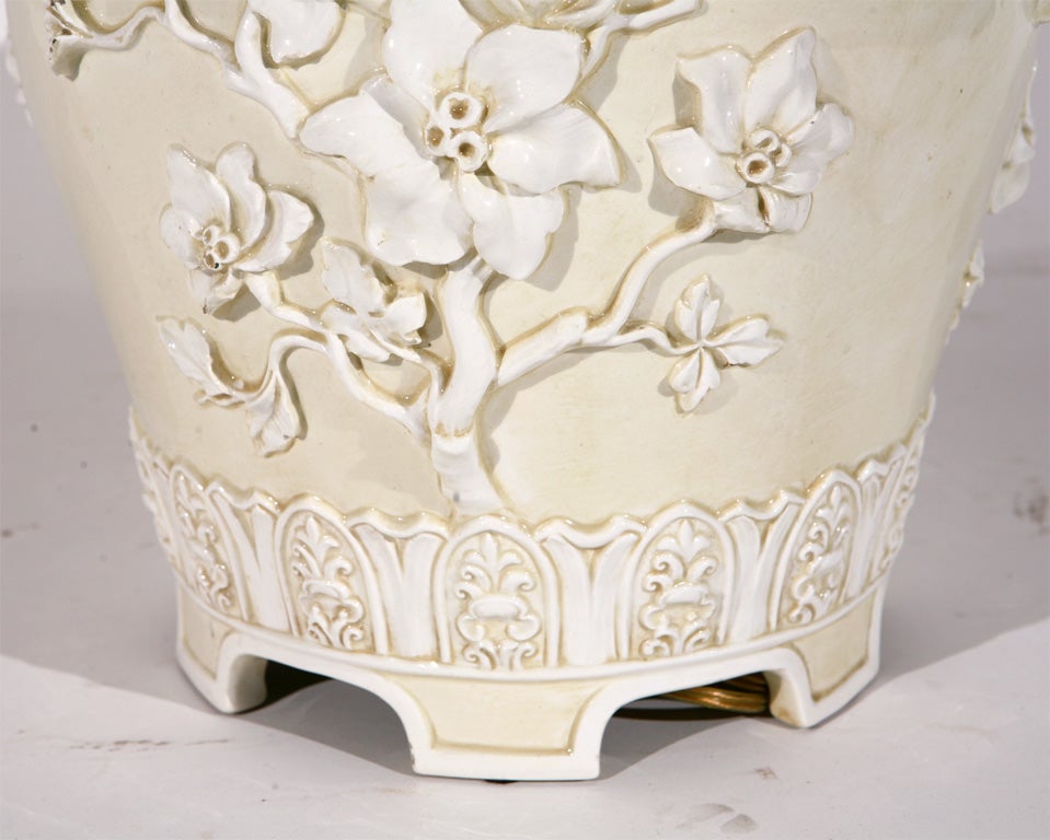Beautiful ceramic lamp featuring delicate white flowers in relief on a cream background. This feminine, asian inspired silhouette would be lovely in a romantic bedroom or light-filled sun porch. 