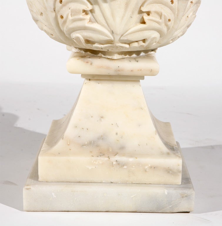 A pair of white marble spheres on bases with acanthus leaf detailing.