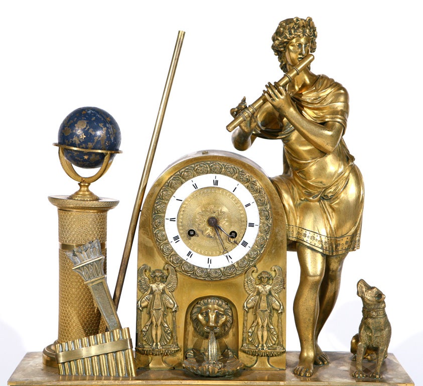 This French clock from the first quarter of the 19th century depicts Apollo playing a flute while his faithful dog looks up at him lovingly. He is leaning on a lion-masked fountain that supports the intricate foliate cast bezel and clock face. Other