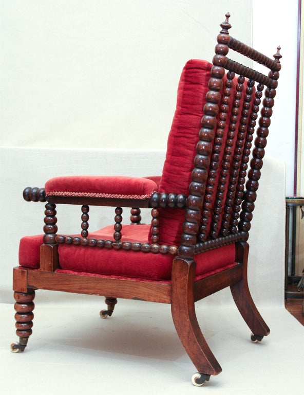 Well-Turned Bobbin Gentleman's Library Chair with Padded Arms Supported by Spindles, Tufted Cushions, and Legs Ending in Original Porcelain Casters. England, c. 1860.<br />
<br />
26 inches wide x 16 inches deep x 42 inches high<br />
Seat Height
