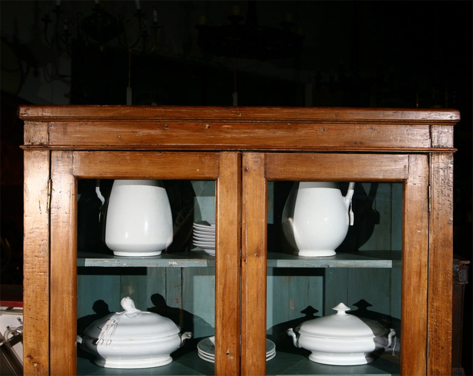 A late 19th century, American, tall cabinet having two glazed doors, four shelves, standing on four feet. The blue interior is well suited for the display of china, glassware and other treasures. Altogether a good furnishing piece. <br />
Jefferson