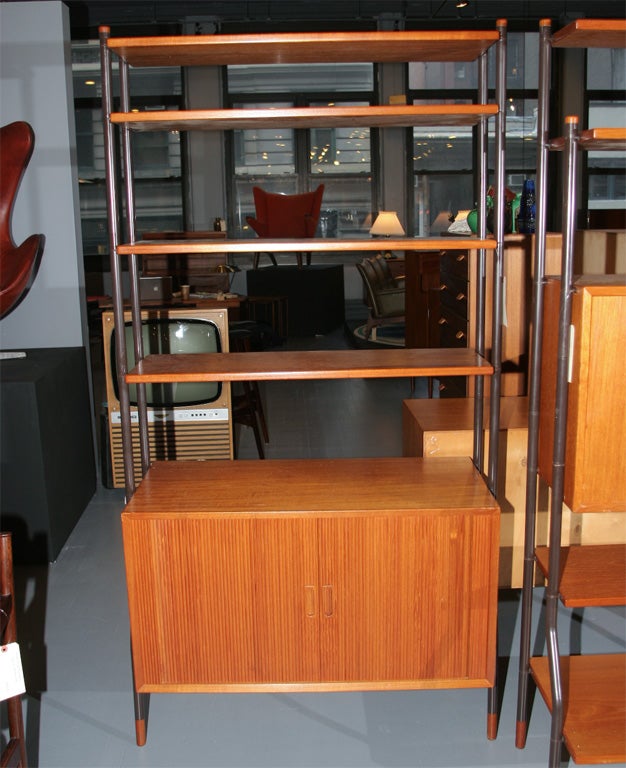 Airy Teak Modular Bookcase with black metal legs, open shelves and teak feet. Cabinet components include tambour doors and shelves.  Only the tambour unit remains available On sale for $2000.