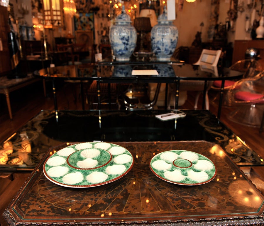 A set of French majolica oyster plates (12 Small plates and 1 Large plate available). with tromp l'oeil basket design, having crackled green glaze and white shell motif with red rope edge. Large plate: 13