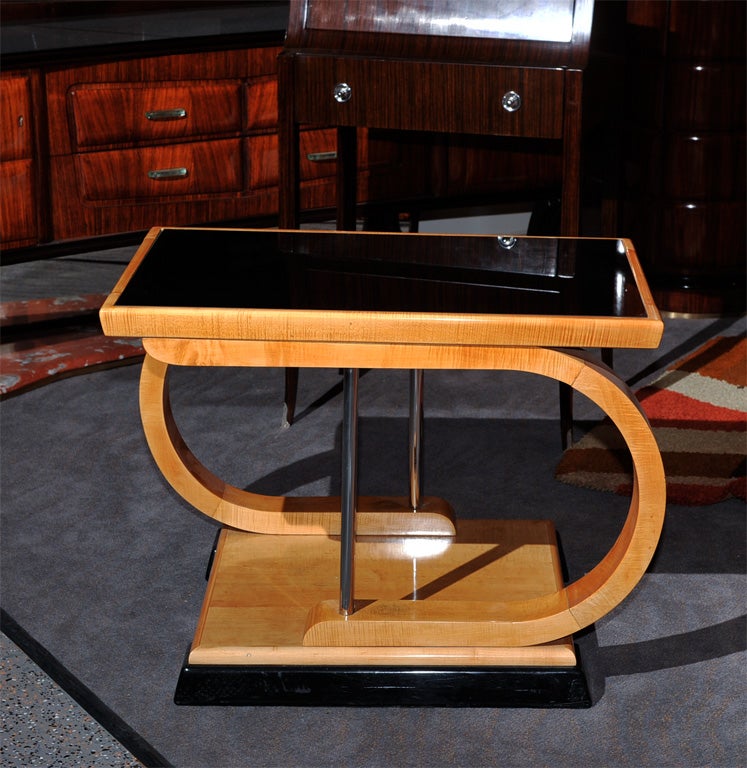 A very unusual shaped table, both in color and treatment. Notice the sweeping asymmetrical likes of the flamed maple wood structure. The minimal use of metal rods to help mirror the opposite images standing on a pair of black lacquer footed skis