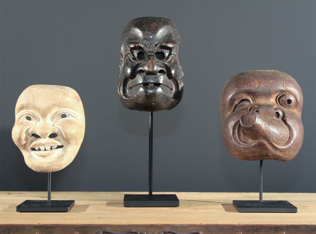 Group of three Japanese carved and painted wood theatrical masks. Each mounted on a contemporary metal stand.<br />
<br />
The masks are also available individually with descriptions and prices below:<br />
<br />
Mask 1 (left): Japanese folk