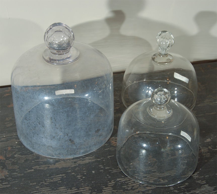 A collection of small hand-blown glass cloches, with blown or cut-glass handles.  Sizes range from about 5