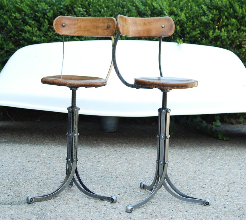 A pair of Industrial Bar Stools with Elm seats and back and a metal tripod base.