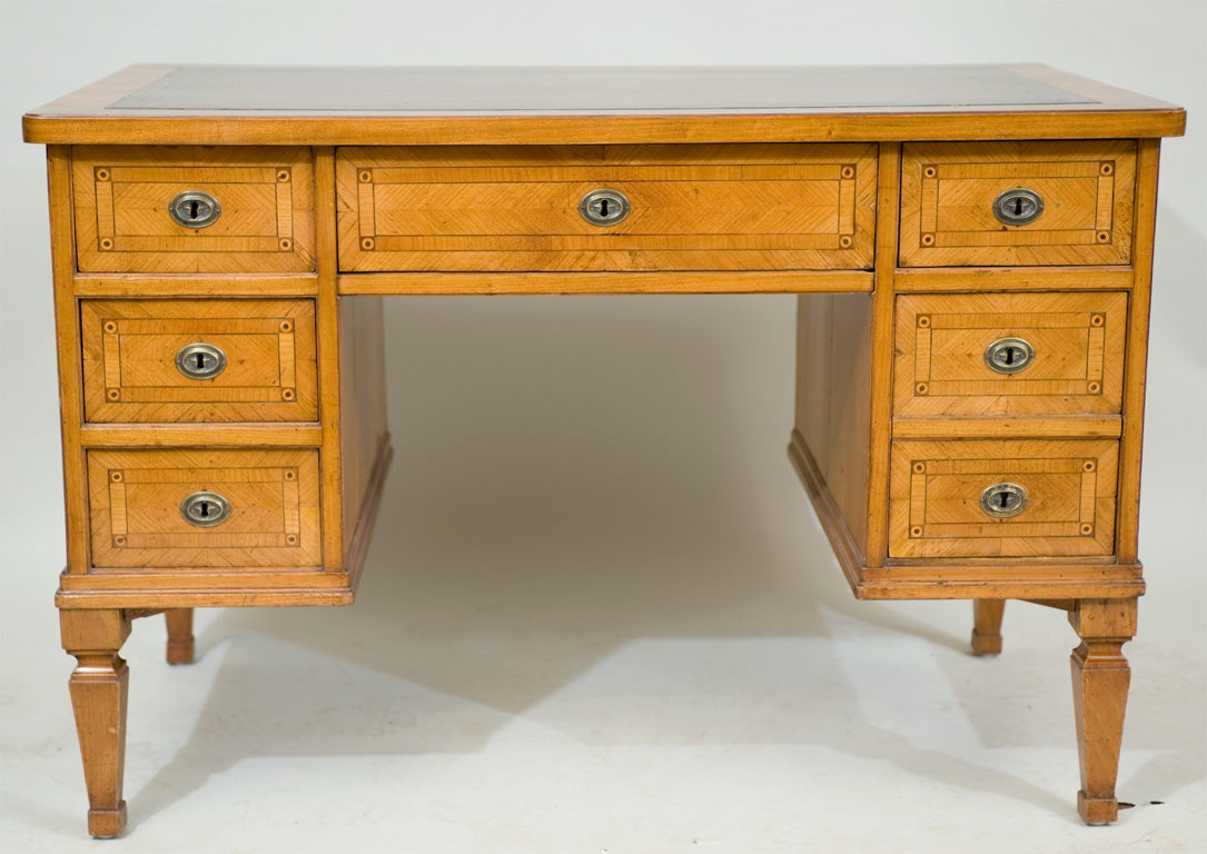 An early 19th century continental walnut inlaid kneehole desk

with an antiqued gold tooled leather top.