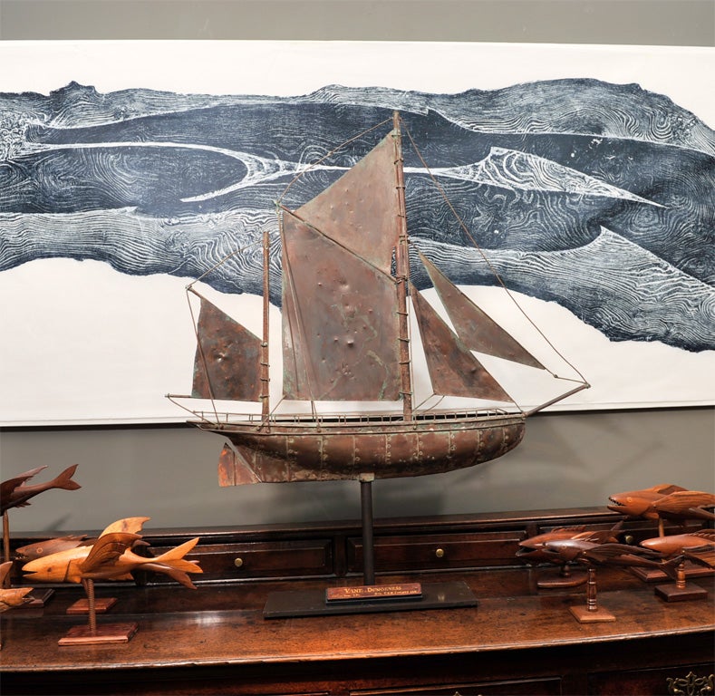 A copper weathervane in the form of a full bodied gaff-rigged sailing boat.  Its wooden museum display label reads 