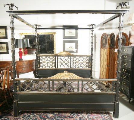 A very rare thoroughly ebonized and parcel-gilded KING-size canopy bed by Maison Jansen. Supported by four ebonized palm-tree shaped columns ending in four leaf-like finials with bell drops; magnificent pierce-carved headboard and footboard with