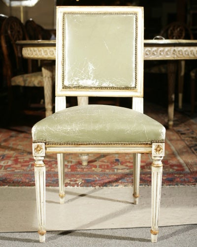 Set of eight fabulous Maison Jansen white painted and parcel-gilded Louis XVI style dining room chairs with distressed green-leather upholstery. Stamped Jansen.