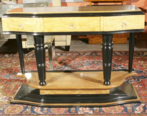 Art Deco style ebonized console table with three serpentine front drawers, standing on four columned legs and serpentine shaped base.