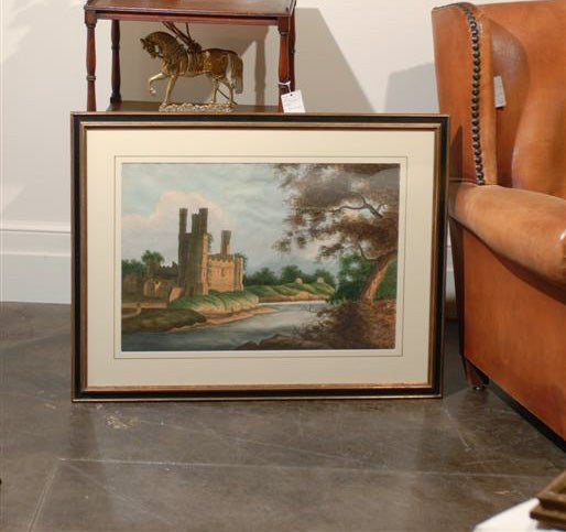 A pair of 19th century English framed watercolor landscapes each with a medieval castle towering a river. The first one depicts a castle illuminated by the sunshine breaking through the foliage on the opposite bank in the foreground. The crenellated