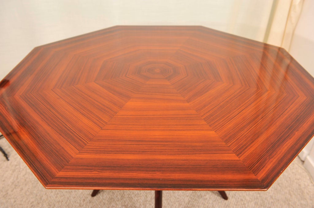 Octagonal dining or center table of rosewood with very graphic top with beveling towards the edges.  Very sculptural base of four tapering legs.